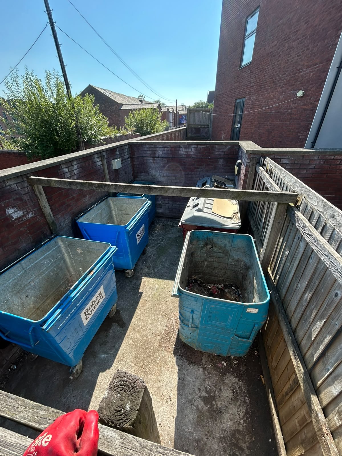 After waste removal: the Bolton bin chamber cleared with empty council bins standing on a clean concrete floor