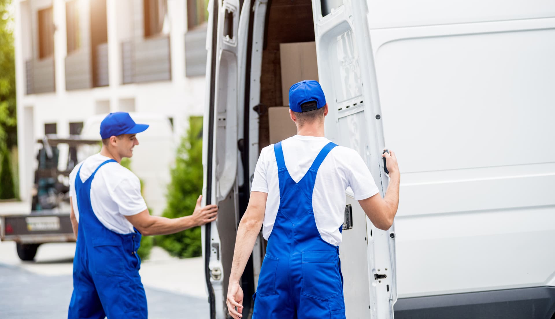 Man and van team loading boxes into a white removals van outside a residential property