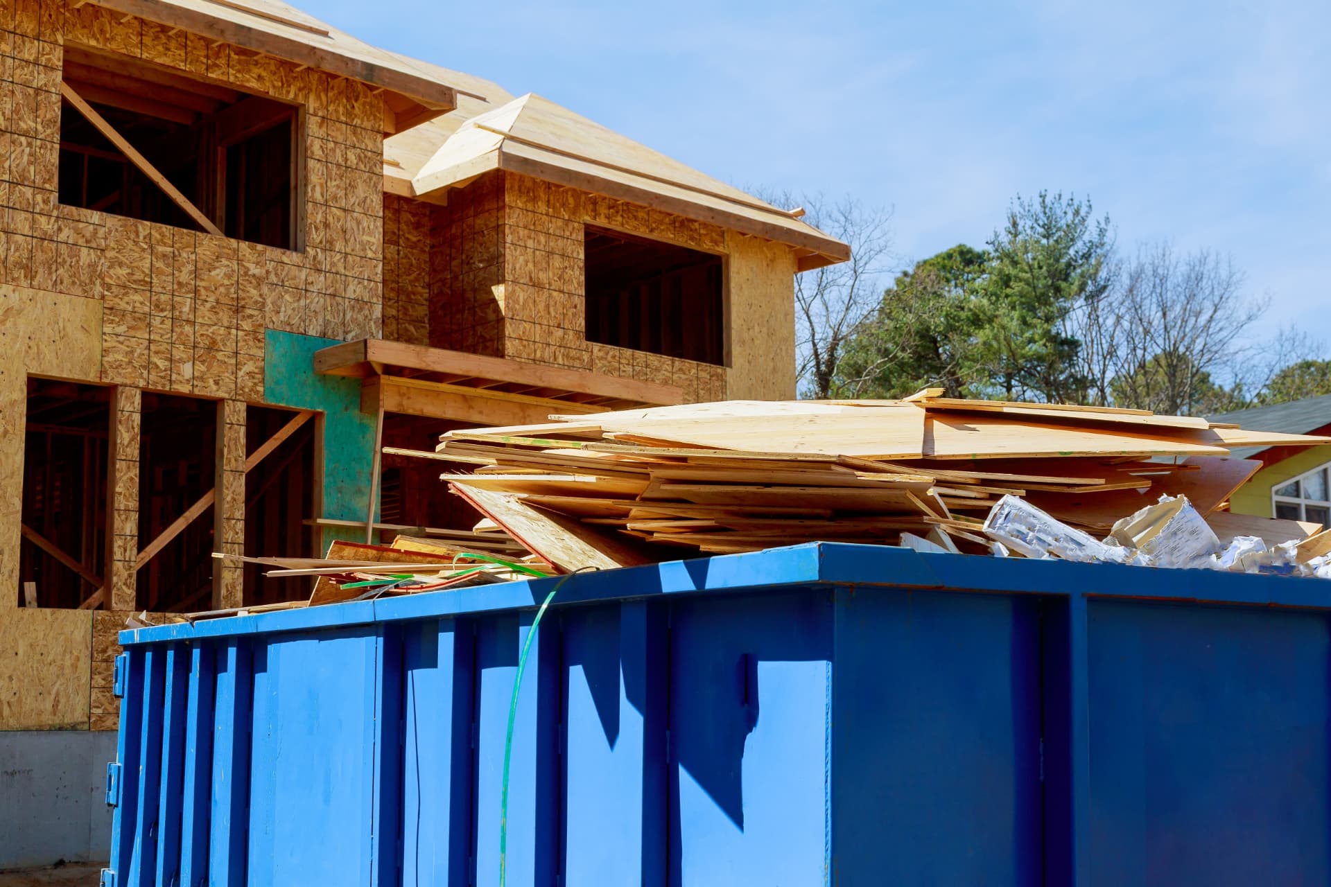 Commercial waste skip filled with timber, plasterboard and building materials outside a construction site