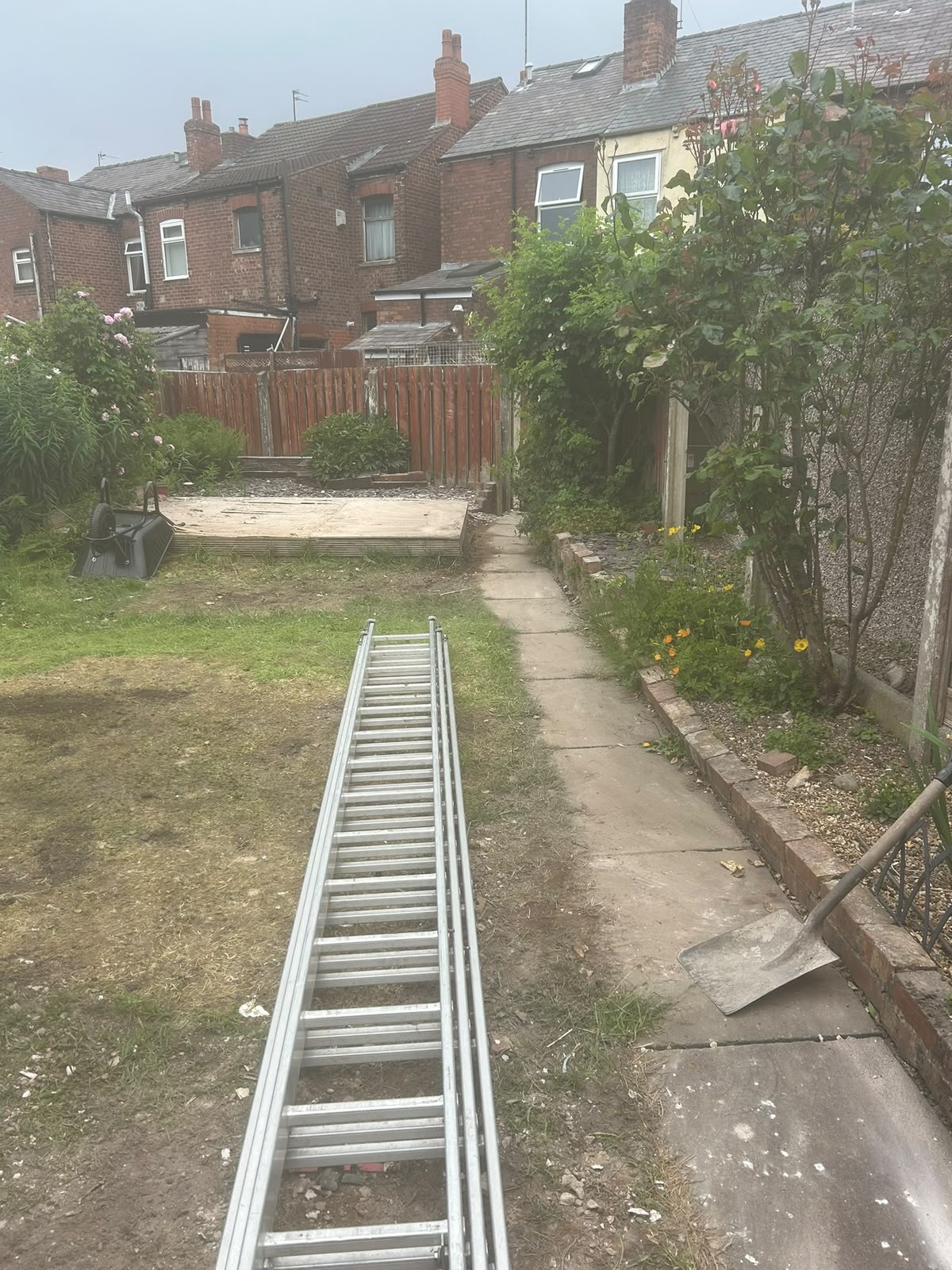 Rear yard behind Manchester terraced housing being cleared of commercial waste with access ladder and equipment in place