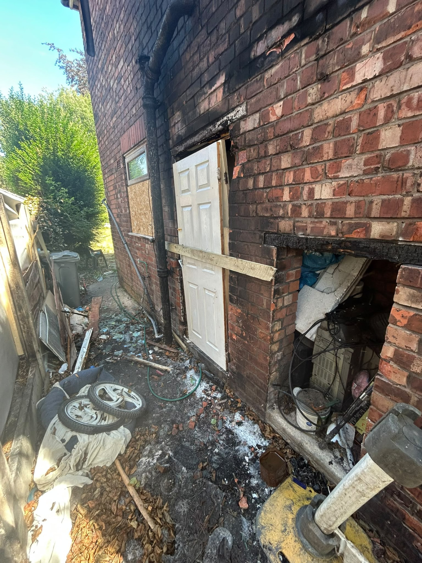 Fire-damaged outbuilding in Manchester with charred masonry and burnt debris awaiting clearance and removal