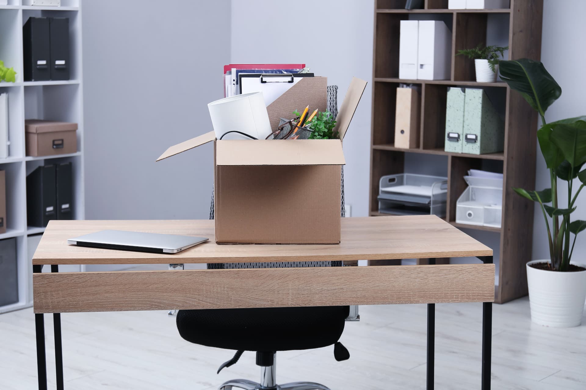 Office desk with a packing box of files and stationery ready for an office clearance