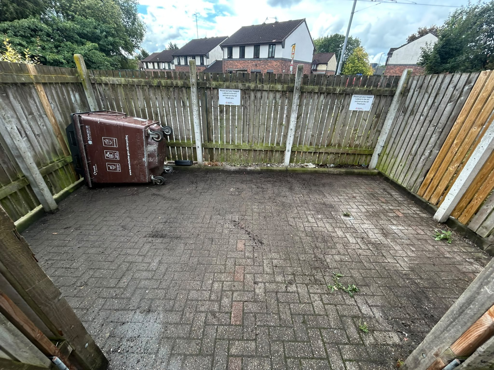 After clearance: the same Manchester communal bin store swept clean with clear block paving and the bin area fully accessible
