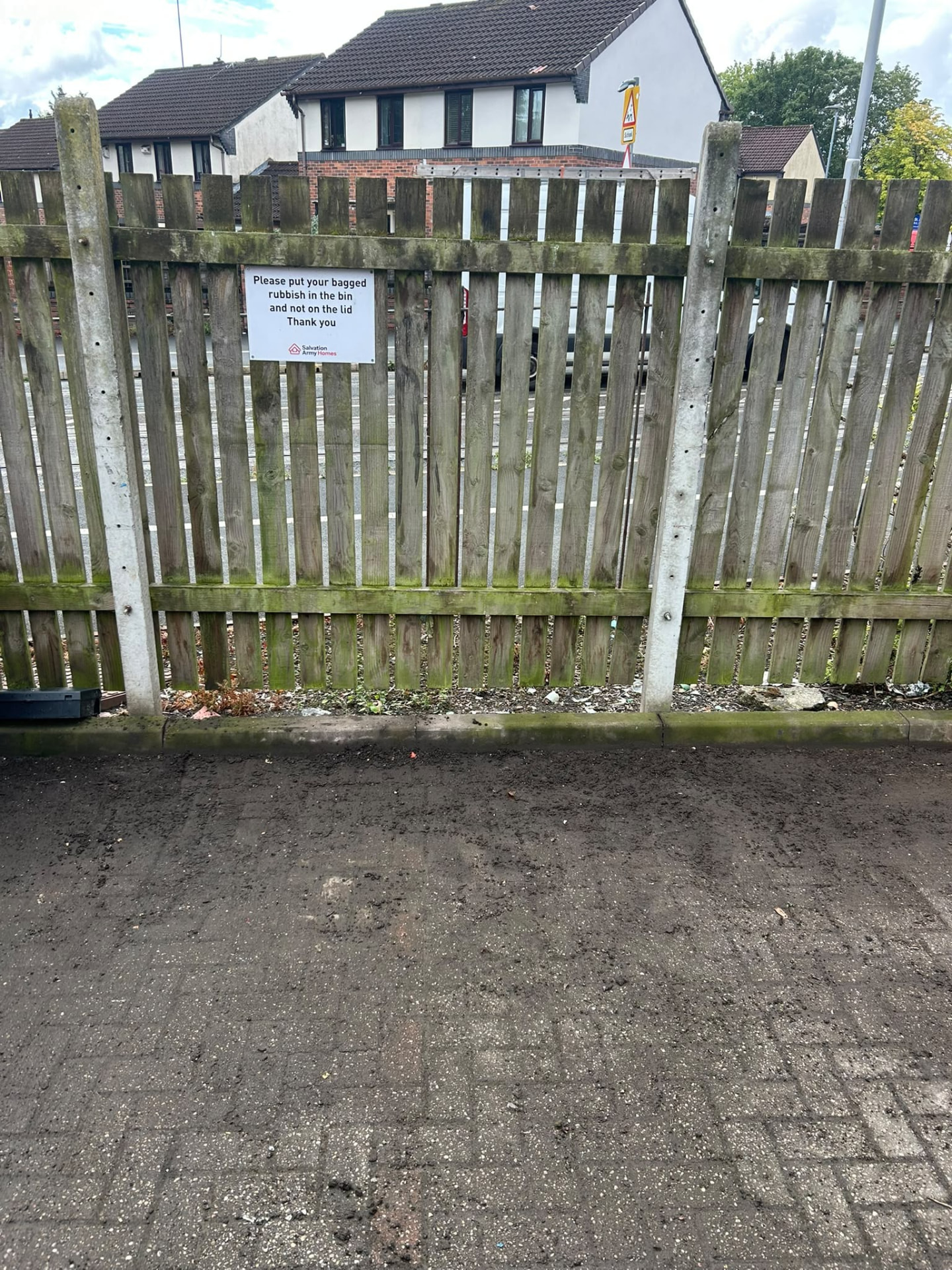 Communal bin store in Manchester cleared of bagged rubbish, with signage asking residents to bag waste