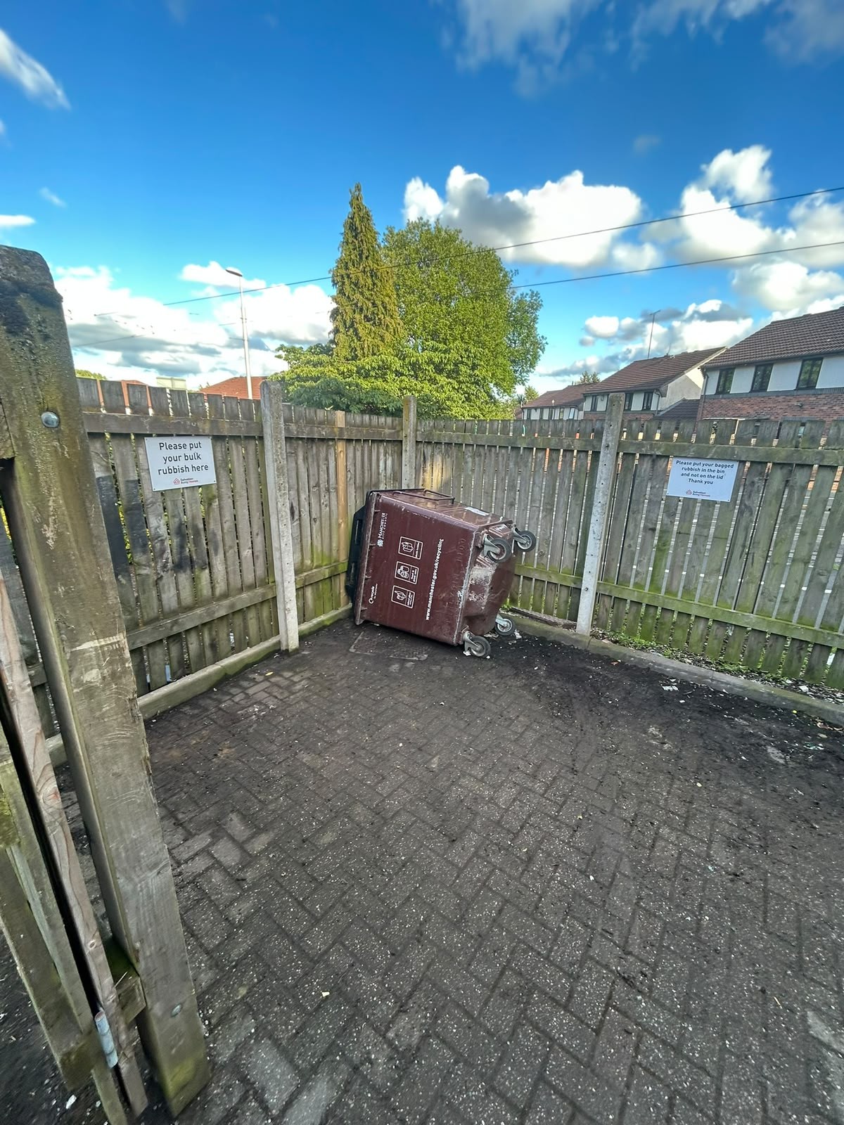 Cleared communal bin area on a Manchester residential block with a single brown wheelie bin left in place